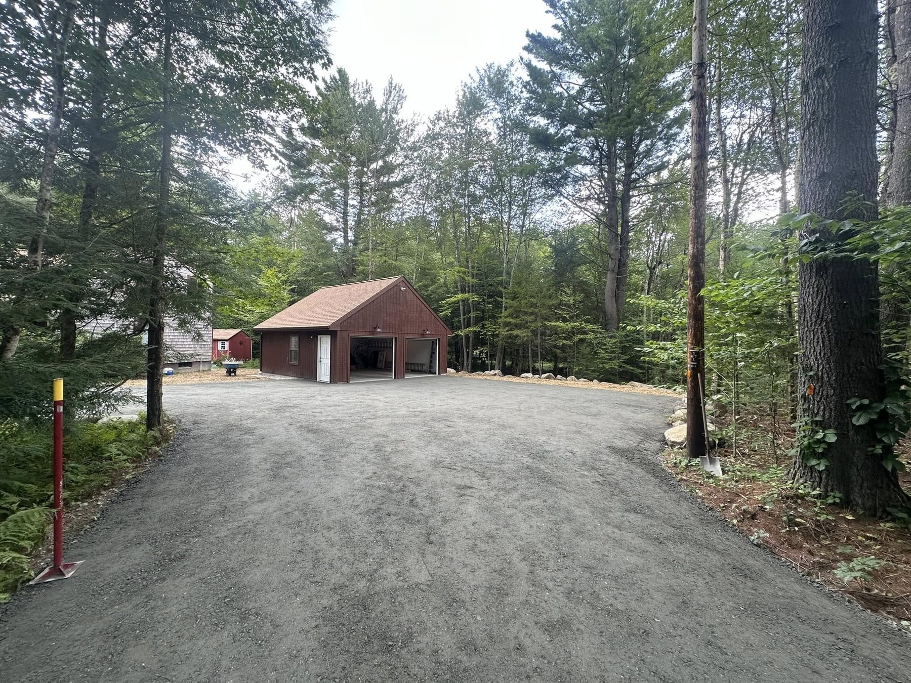 Gravel driveway leading through pines to a barn