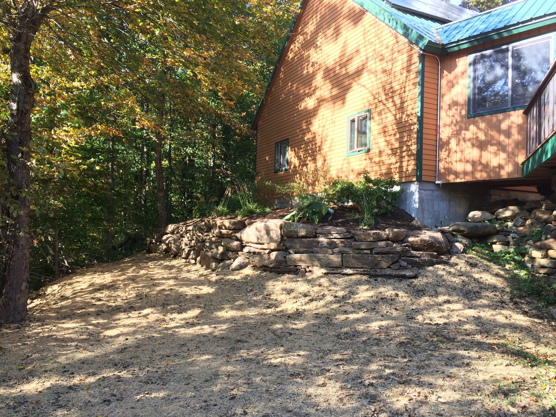 Fieldstone retaining wall beside a house in autumn