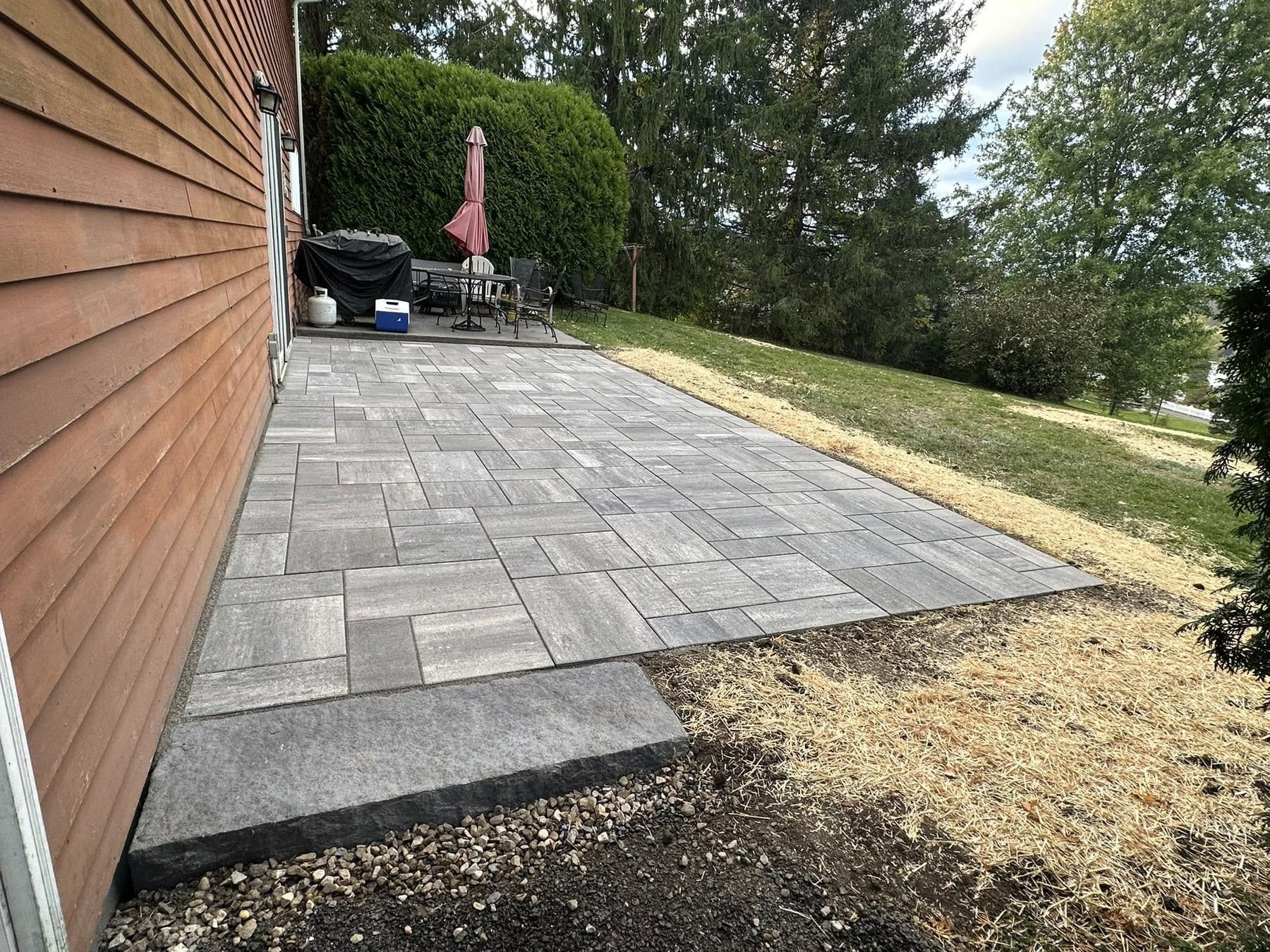 Paver patio installed along the side of a house