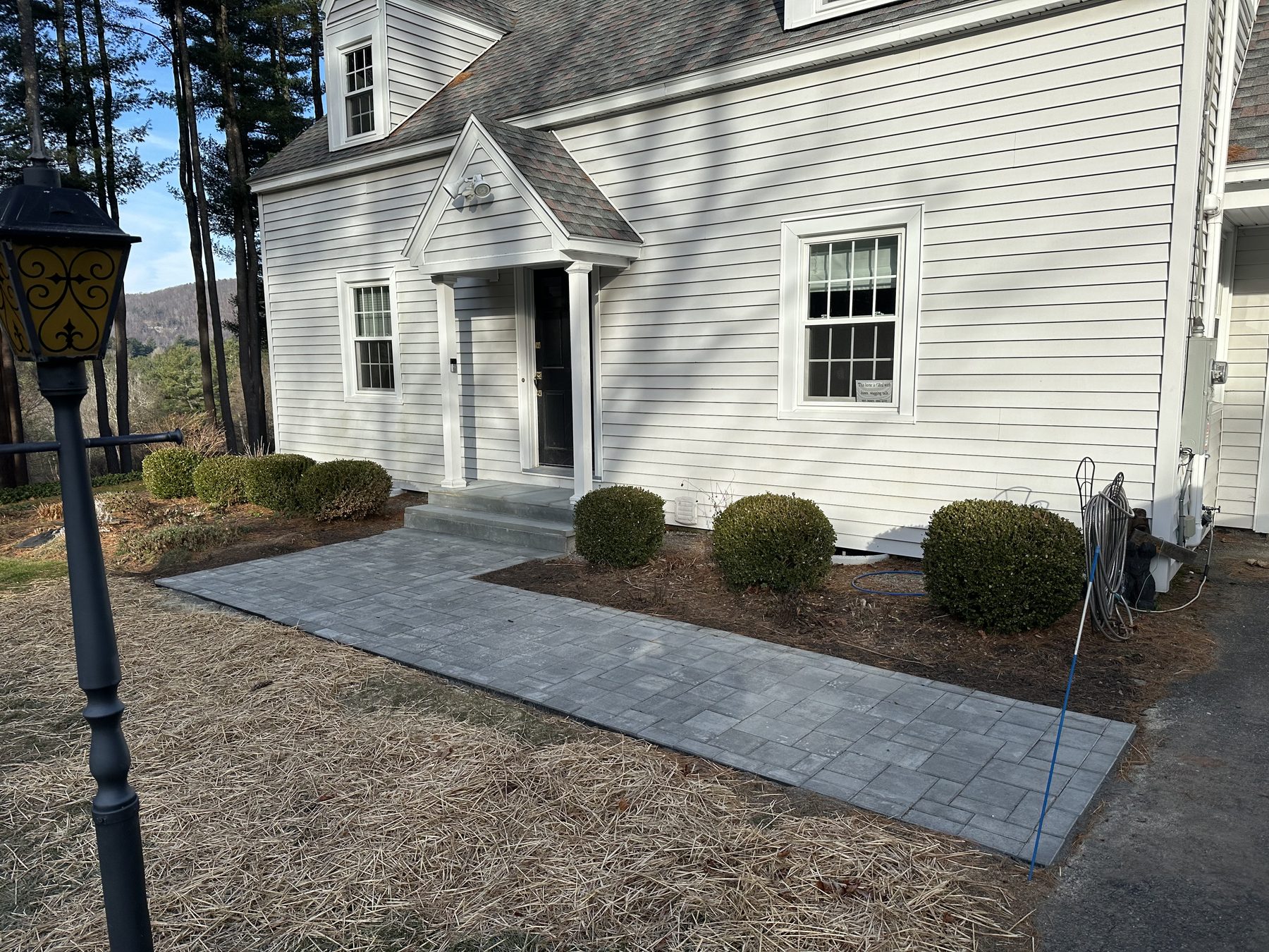 Paver walkway to a front entry with clipped shrubs