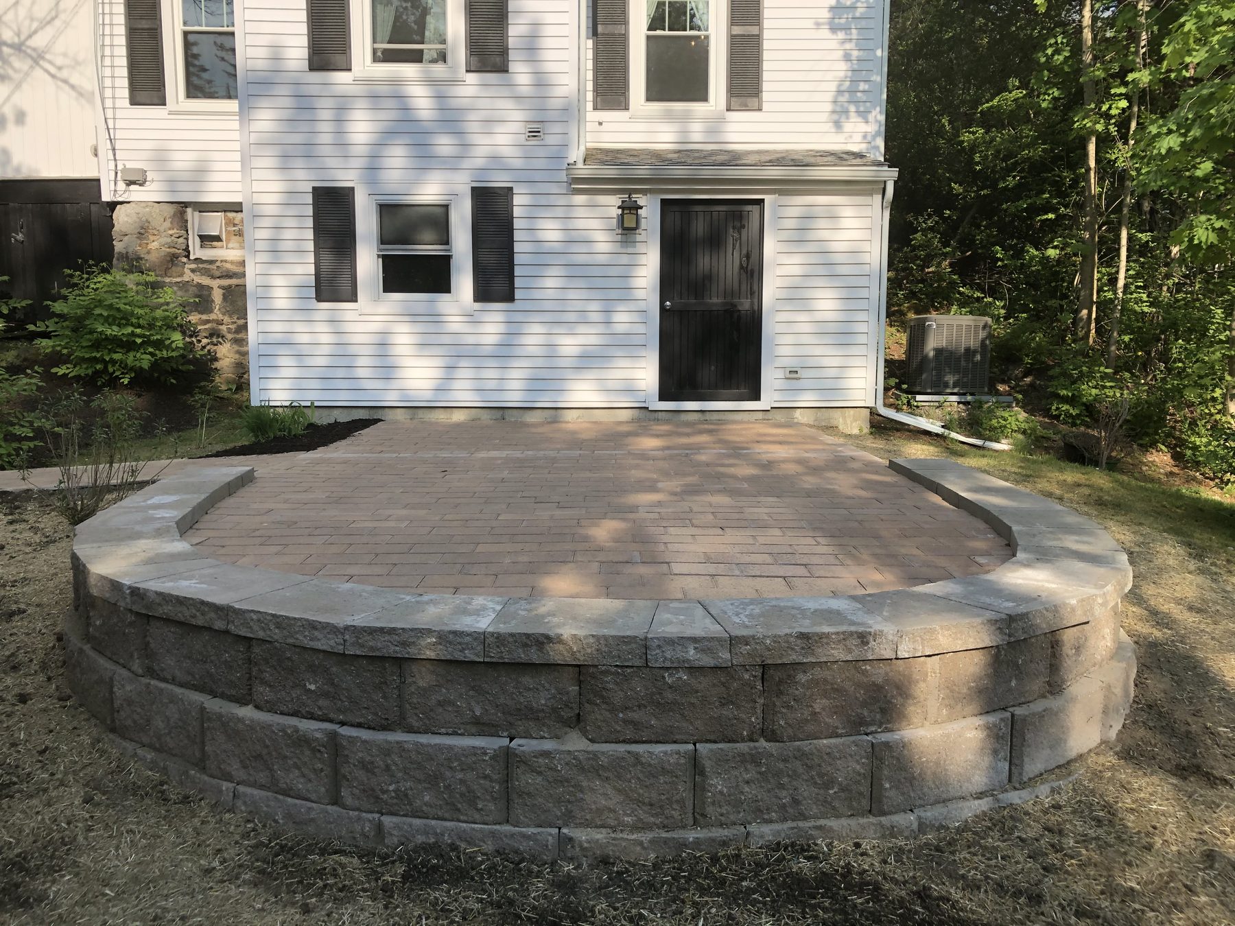 Raised circular paver patio with a curved seat wall