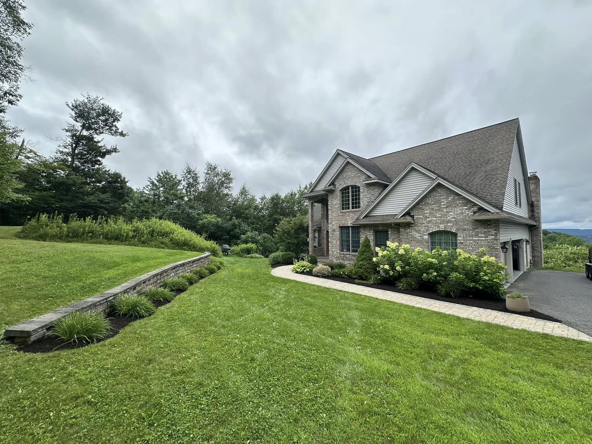 Stone home with a low retaining wall and established lawn in Berkshire County