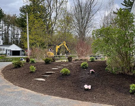 Curved mulch bed with stepping stones and new plantings