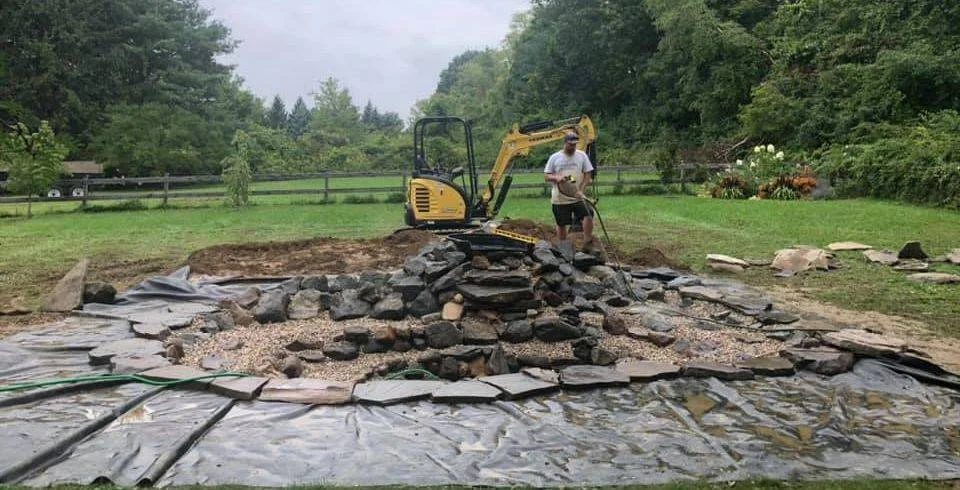 Waterfall stone being placed during a pond build